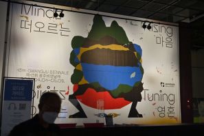 A visitor walks past a poster for the 13th Gwangju