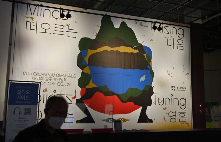 A visitor walks past a poster for the 13th Gwangju