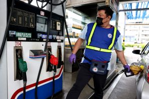 A petrol station worker refuels a car at a gas