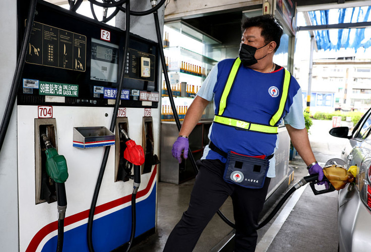 A petrol station worker refuels a car at a gas